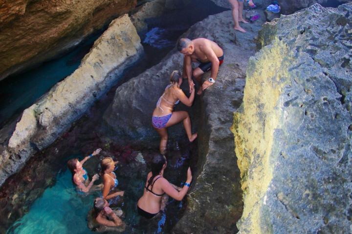 a man swimming in water next to the rock