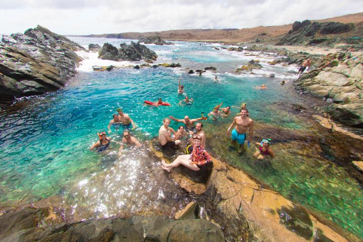 a group of people sitting on a rock next to a body of water