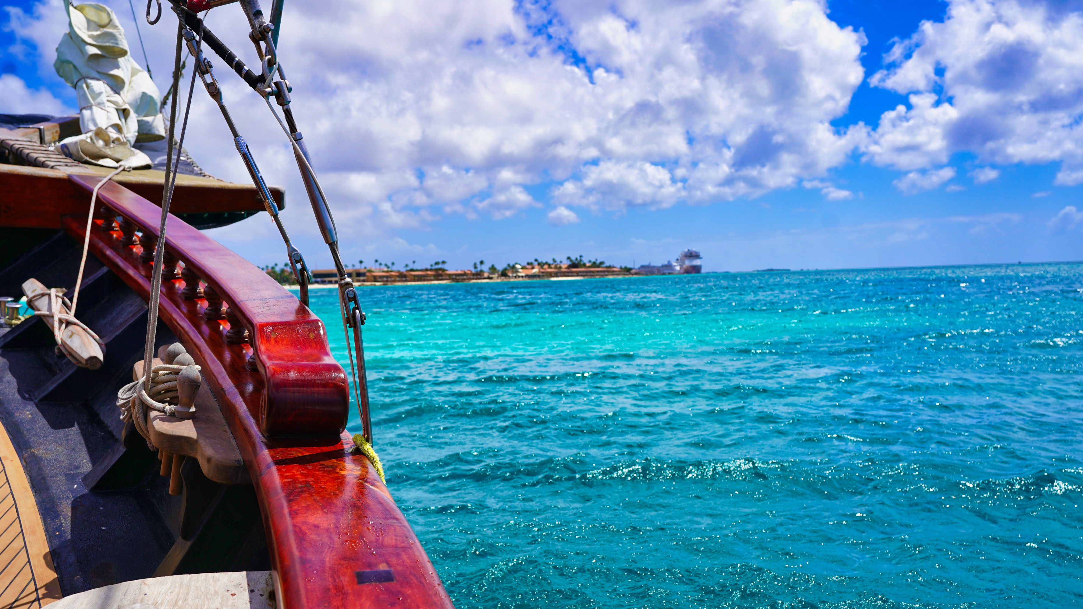 View from a boat on turquoise sea under clouded sky, distant island visible.